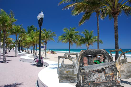 photoshoped picture of a burned out car on the beach with two polo players in it